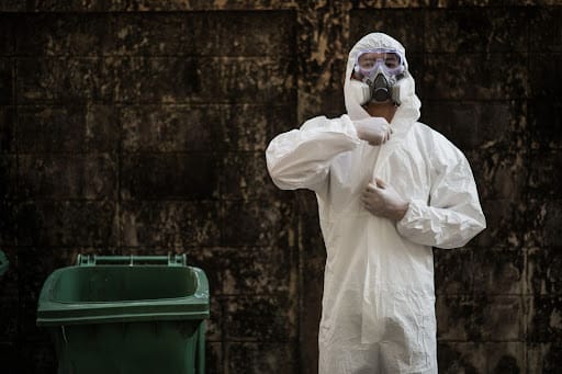 Man dressing in protective clothing to prepare to safely clean up mouse droppings